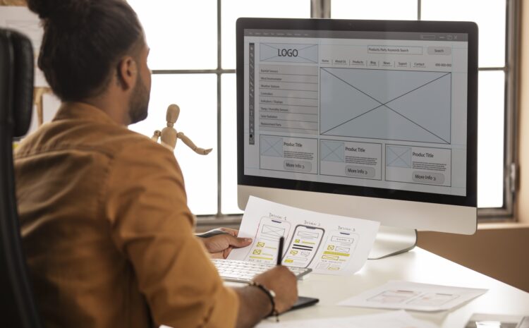 Developer comparing printed UX design to mockup on computer screen.