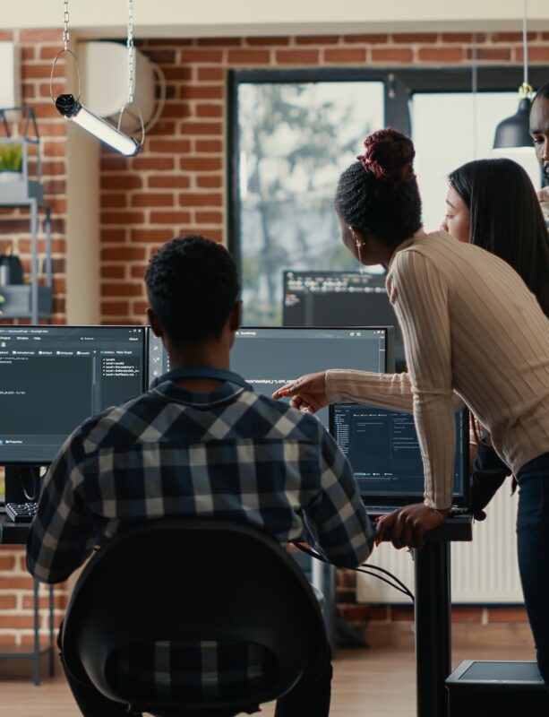 Development Team Development team standing around computer monitors in a discussion.