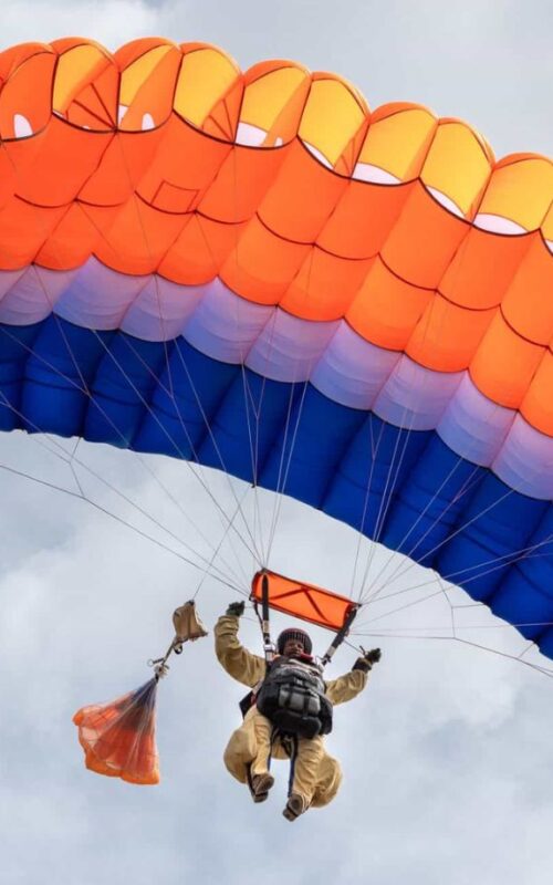 Smokejumper parachuting in a cloudy sky.