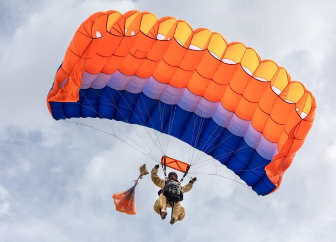 Smokejumper parachuting in a cloudy sky.