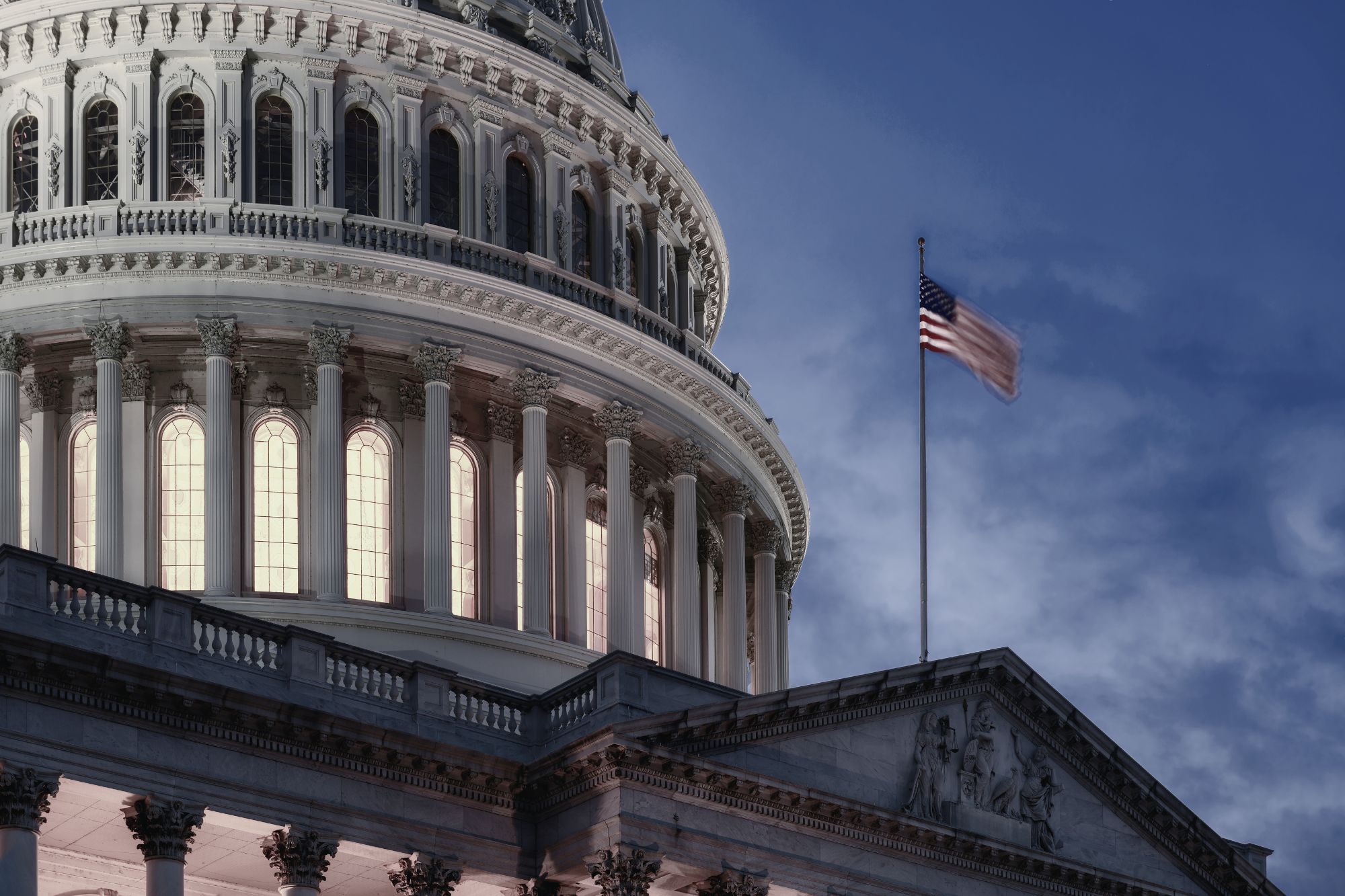 Closeup of the US Capitol building and the US Flag flight full staff