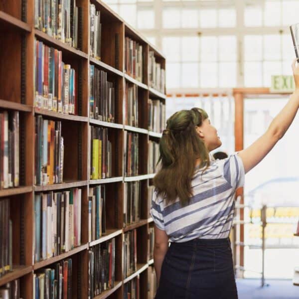 student reaching for a book in a library